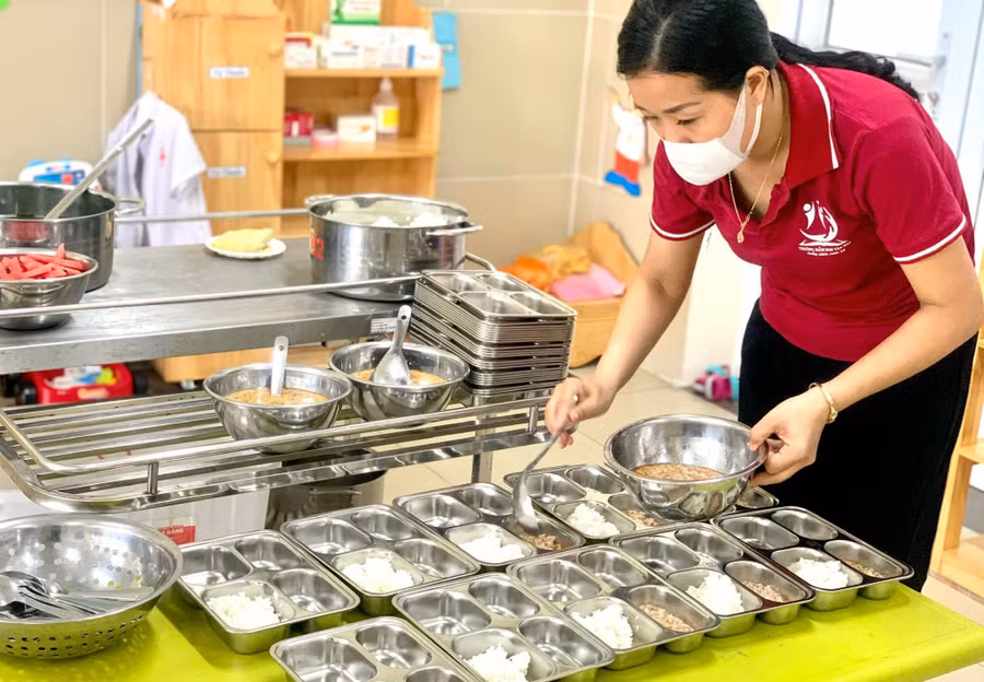 Cô nuôi Trường Mầm non Tân Mai chia cơm cho trẻ. Ảnh: NTCC