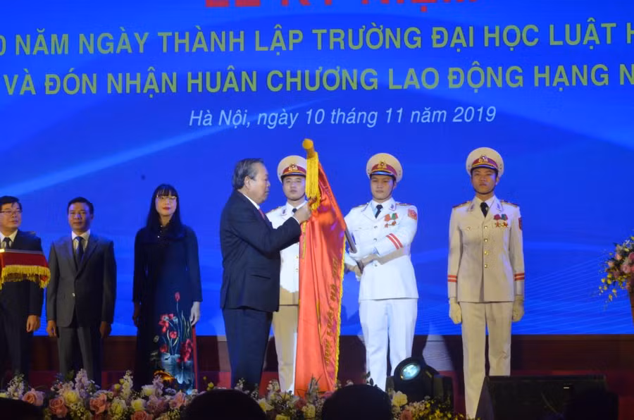 Phó Thủ tướng Chính phủ Trương Hòa Bình gắn Huân chương trong nghi lễ đón nhận Huân chương Lao động hạng nhất của Trường ĐH Luật Hà Nội.