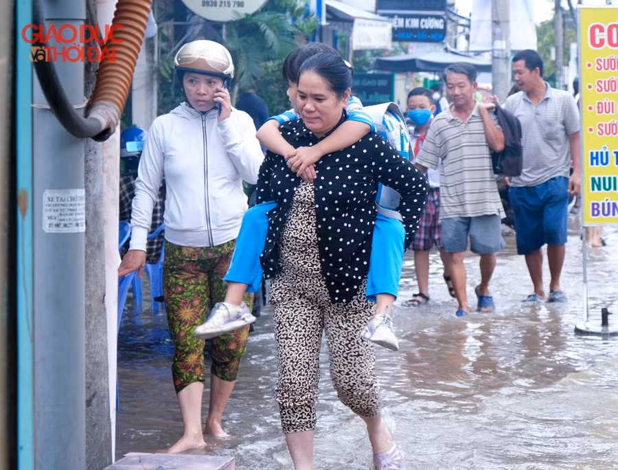 Nước ngập, nhiều phụ huynh phải cõng con đến trường.