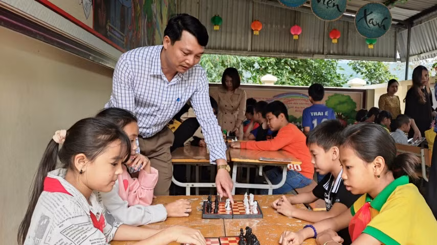 Thầy Đặng Xuân Viên hướng dẫn học trò chơi cờ vua ở trong thư viện xanh của trường. Ảnh: TG