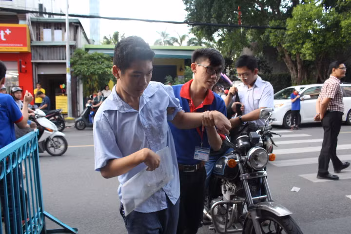 Một thí sinh đặc biệt tại điểm thi Trường THCS Colette được sinh viên tình nguyện hỗ trợ vào điểm thi