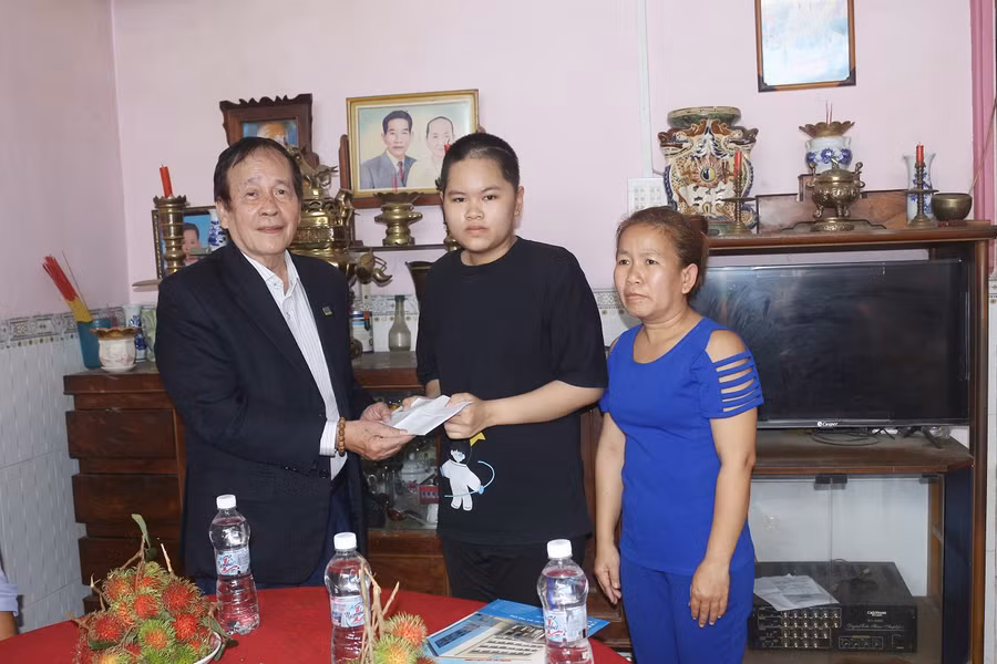 Thạc sĩ Nguyễn Cao Đạt - Chủ tịch Hội Khuyến học Trường ĐH Cửu Long trao tiền hỗ trợ cho em Trúc Đào.