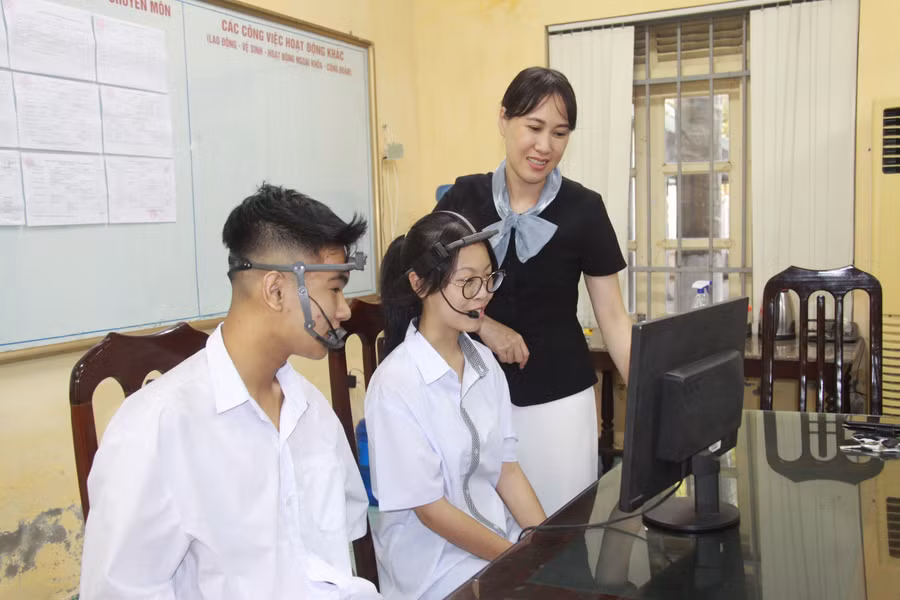 Cô Ánh Tuyết (phải) hướng dẫn Trần Trọng Bách (trái) và Nguyễn Minh Tú điều khiển thiết bị. 
