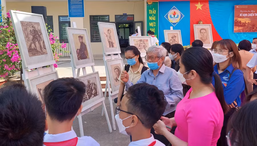 Giáo viên và học sinh Trường THCS Nguyễn Văn Linh (huyện Hòa Vang) chăm chú lắng nghe họa sĩ – nhà điêu khắc Phạm Hồng kể lại những câu chuyện đằng sau các bức ký họa chiến trường trong triển lãm lưu động Ký họa chiến trường khu V. 