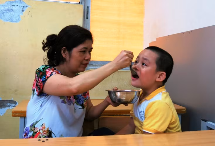 Cô Thủy dỗ dành trò khuyết tật trong giờ ăn trưa Cô Thủy dỗ dành trò khuyết tật trong giờ ăn trưa