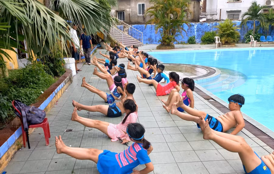 Học sinh tập các bài tập khởi động trước khi bơi.
