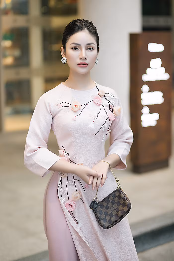 Trong những ngày cuối năm, cô chọn 1 chiếc áo dài thật nhã nhặn để xuống phố, họa tiết đính hoa ở trên áo cùng tông hồng với quần.&nbsp;Mái tóc búi thấp cổ điển, kèm theo bông tai đá lấp lánh làm tăng thêm vẻ kiêu sa, đài các.