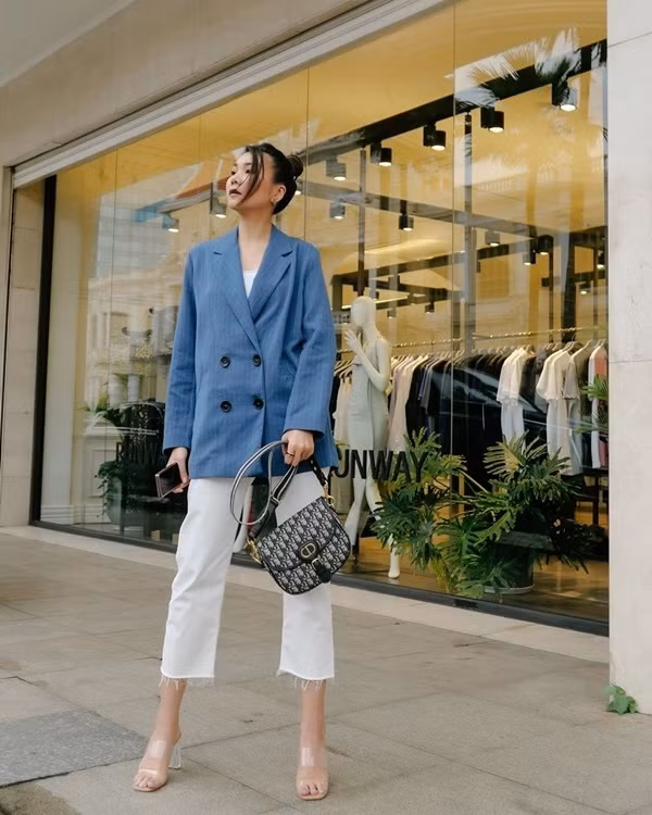 Xuống phố ngày thu, Thanh Hằng ưu ái diện blazer mỏng phối cùng quần jeans trắng dáng lửng. Để nhấn nhá lợi thế chân dài, siêu mẫu mang sandals cao gót quai trong suốt. Cô nàng còn cố ý điểm xuyết nét thanh lịch bằng túi xách Bobby, họa tiết oblique của Dior.