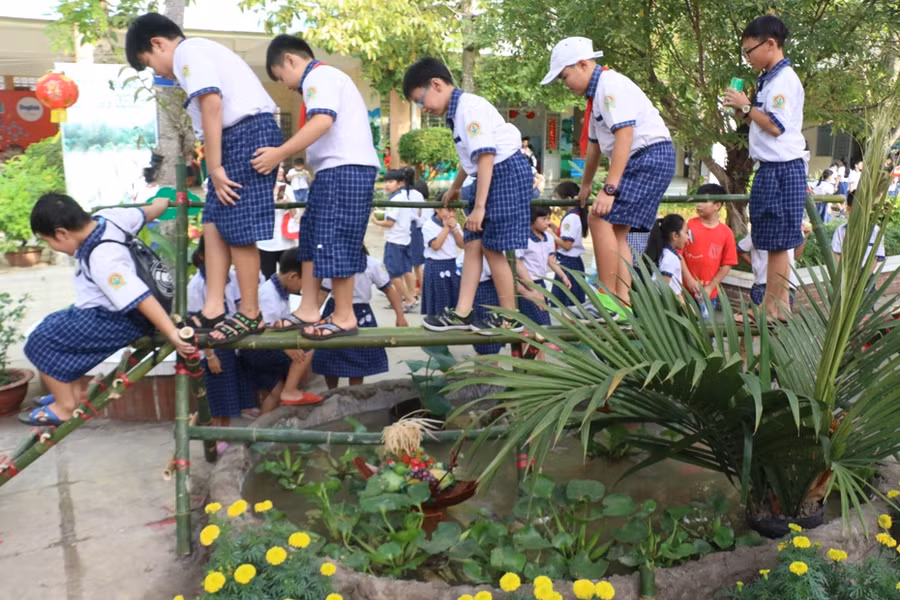 Các em học sinh thích thú trải nghiệm đi cầu khỉ chỉ có ở vùng quê.