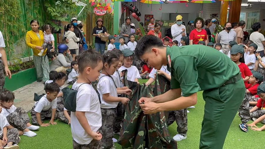 Các bé Trường Mầm non Ngọc Lan được chú bộ đội hướng dẫn cách gấp chăn trước khi vào nội dung thi.