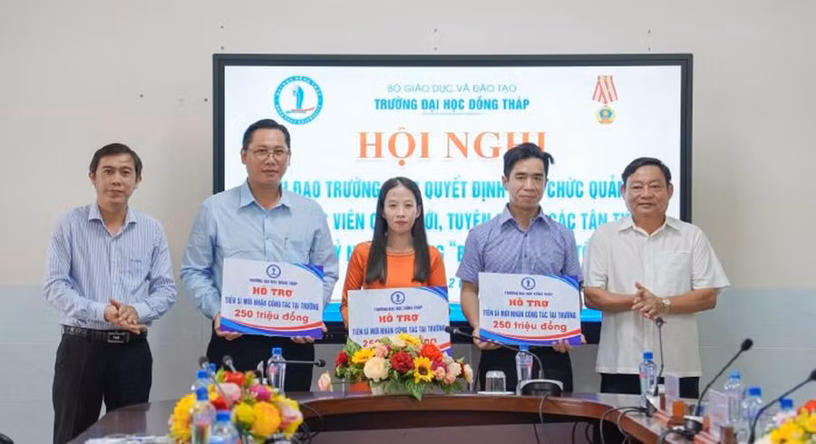 TS Trương Tấn Đạt, Chủ tịch Hội đồng trường (trái) và PGS.TS Hồ Văn Thống, Hiệu trưởng trao hỗ trợ viên chức tuyển dụng mới có học vị Tiến sĩ.