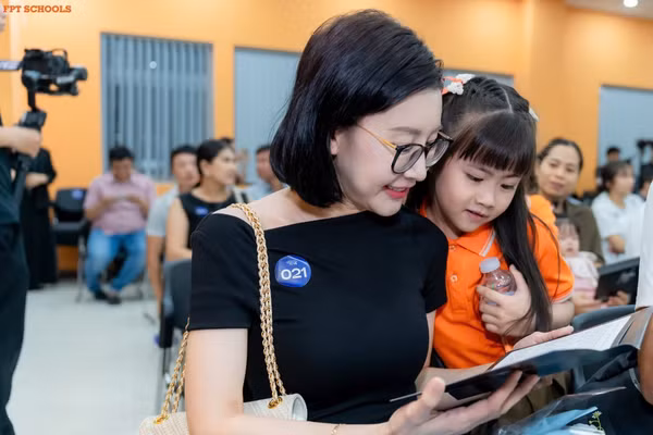 Phụ huynh cùng con xem thư tay nhà trường gửi nhân dịp bế giảng năm học.
