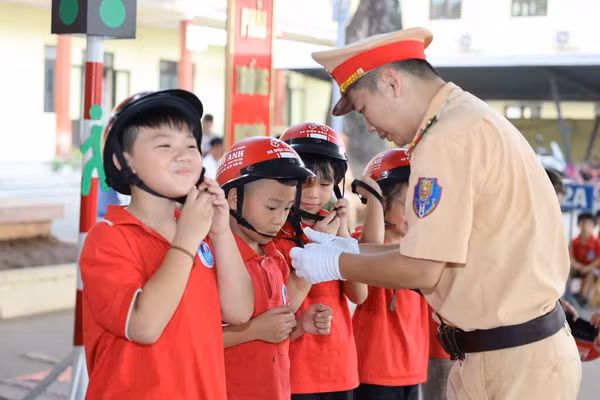 Học sinh được Cảnh sát giao thông hướng dẫn sử dụng mũ bảo hiểm.