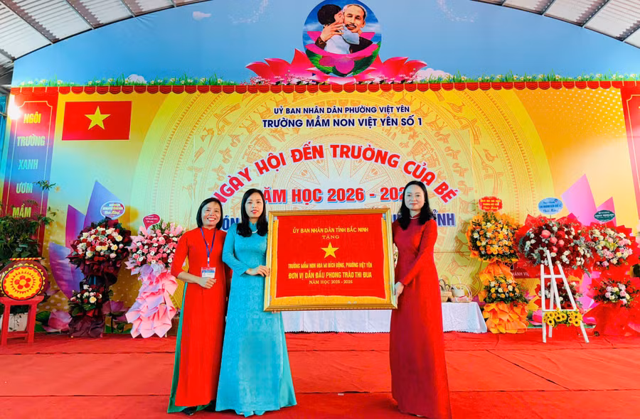 Thừa ủy quyền, bà Đỗ Thị Hương, Phó Chủ tịch UBND phường Việt Yên (bên phải) trao Cờ thi đua cho nhà trường.