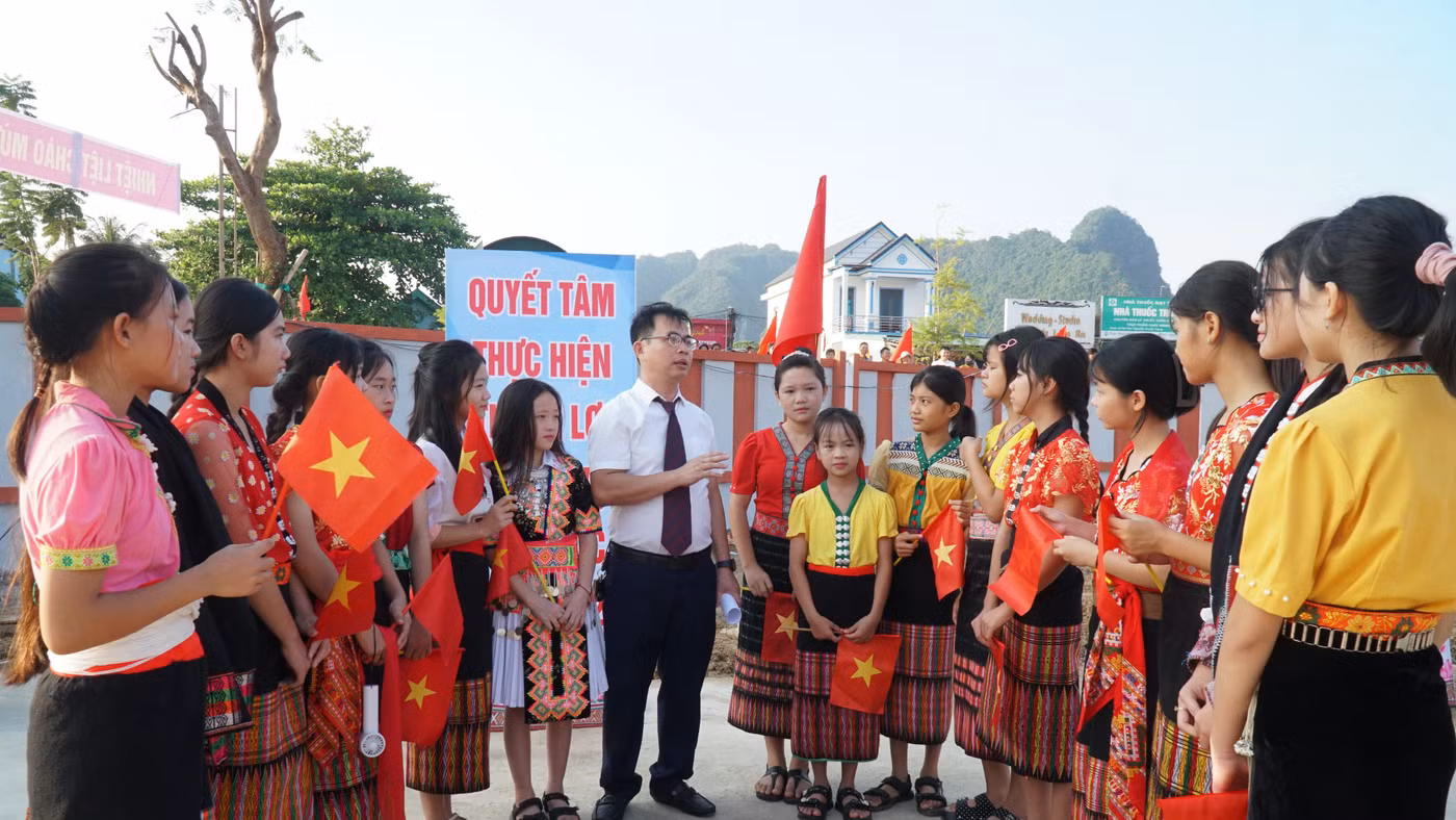 Thầy Nguyễn Lê Tú - giáo viên Trường Phổ thông nội trú TH&THCS Anh Sơn (Nghệ An) đón học sinh từ bản Cao Vều. Ảnh: Hồ Lài