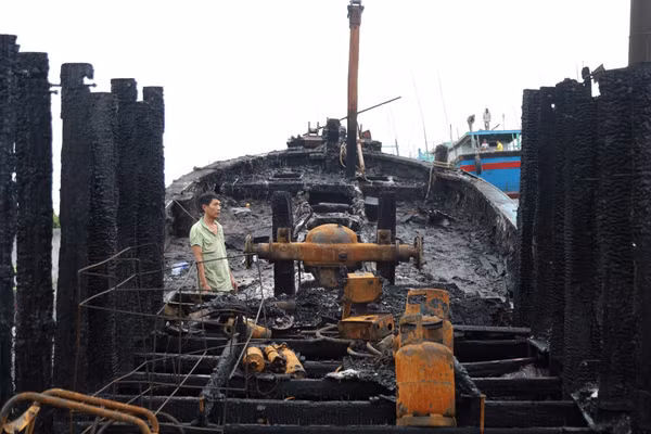Đứng giữa xác tàu cháy đen, người ngư dân lặng người trước mất mát quá lớn.