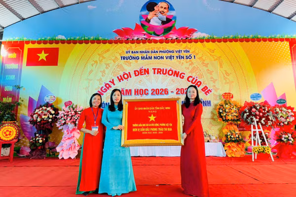 Thừa ủy quyền, bà Đỗ Thị Hương, Phó Chủ tịch UBND phường Việt Yên (bên phải) trao Cờ thi đua cho nhà trường.