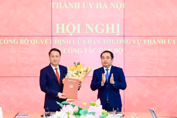 Bí thư Thành ủy Hà Nội Trần Đức Thắng trao quyết định và tặng hoa chúc mừng ông Trần Đình Cảnh. Ảnh QT.