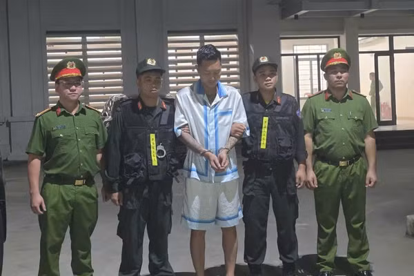 Bị can Bùi Xuân Huấn (đứng giữa) tại cơ quan công an.