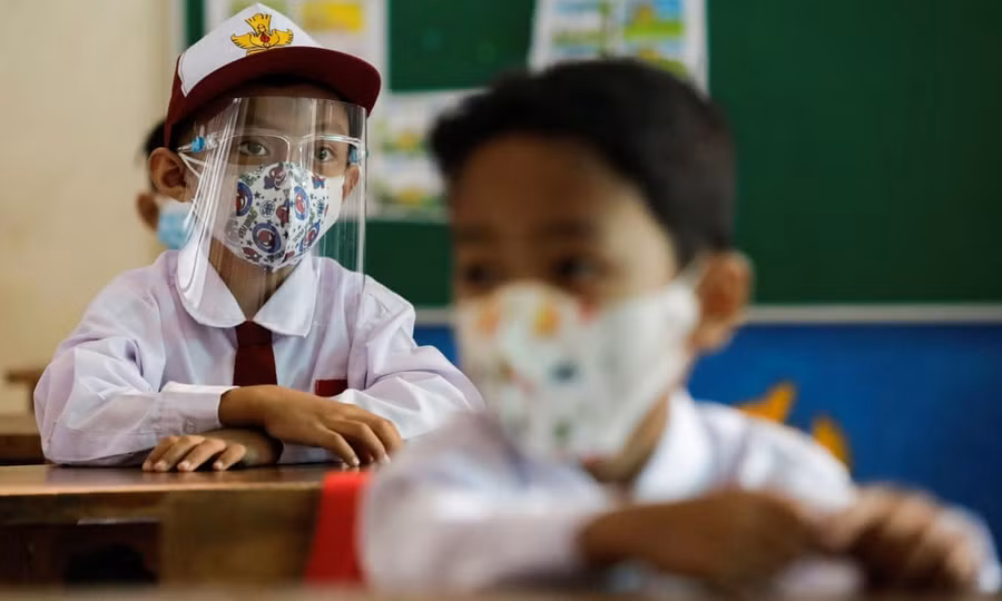 Học sinh Indonesia đeo kính chắn giọt bắn trong lớp học. Ảnh: Guim.