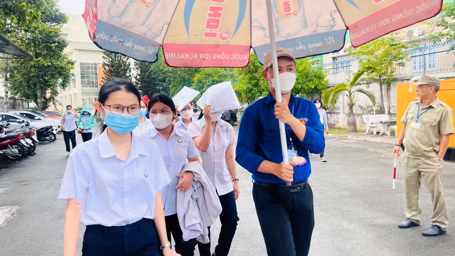 Các thí sinh được các tình nguyện viên che dù từ phòng thi ra cổng. Các thí sinh được các tình nguyện viên che dù từ phòng thi ra cổng.