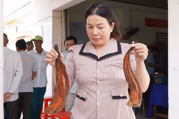 Bà Huỳnh Thị Lệ mang cá chết đến cuộc họp.