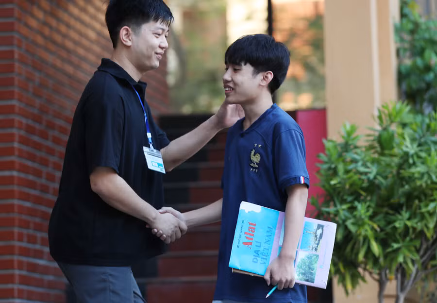 Thầy Trần Đình Huy - trực tại trường 24/24 trong những ngày thi, phụ trách quản lý học trò ở nội trú. Trước buổi thi quan trọng, thầy giáo trẻ bắt tay động viên thí sinh - giống như mình nhiều năm trước cũng từng là học trò nội trú. Ảnh: Hồ Lài.