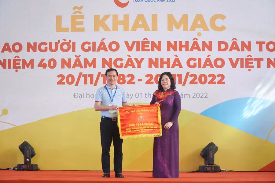Thứ trưởng Bộ GD&amp;ĐT Ngô Thị Minh trao cờ cho đơn vị đăng cai là Trường Đại học Vinh.