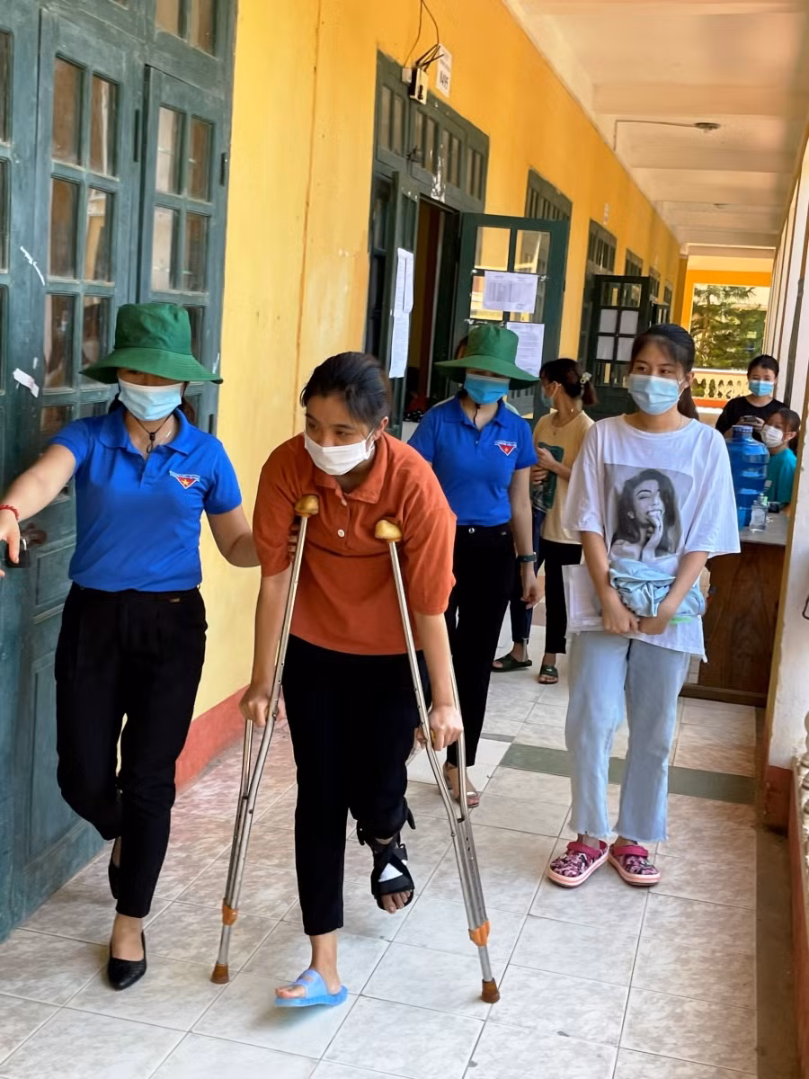 Dìu thí sinh vào phòng làm thủ tục dự thi.