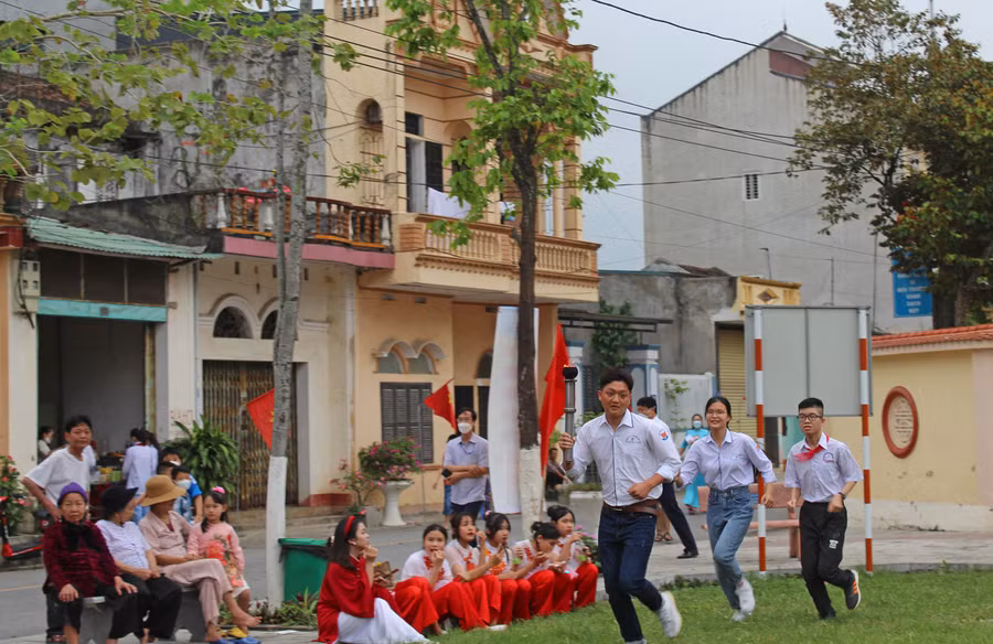 Ba học sinh có thành tích xuất sắc đại diện cho thế hệ HS Hoằng Hóa dẫn ngọn đuốc rực cháy từ di tích Bảng Môn Đình ra khu vực sân khấu.
