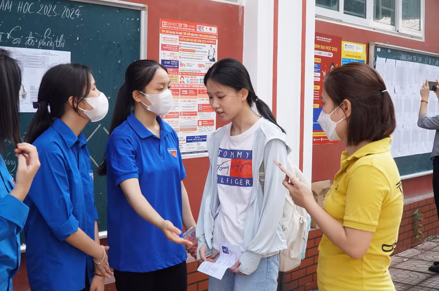 Đội tình nguyện viên hướng dẫn thí sinh và phụ huynh tìm đúng phòng thi tại Trường THPT Huỳnh Thúc Kháng, TP Vinh, Nghệ An. Ảnh: Hồ Lài.