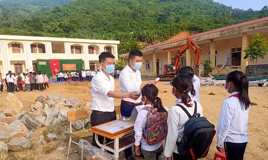 Thầy giáo kiểm tra thân nhiệt cho học sinh Trường THCS Mường Chanh.