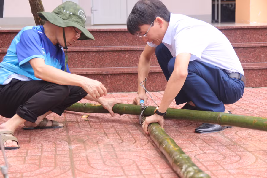 Dùng dây thép và kìm buộc các cây mét lại với nhau làm vật chống đỡ cho cây xanh