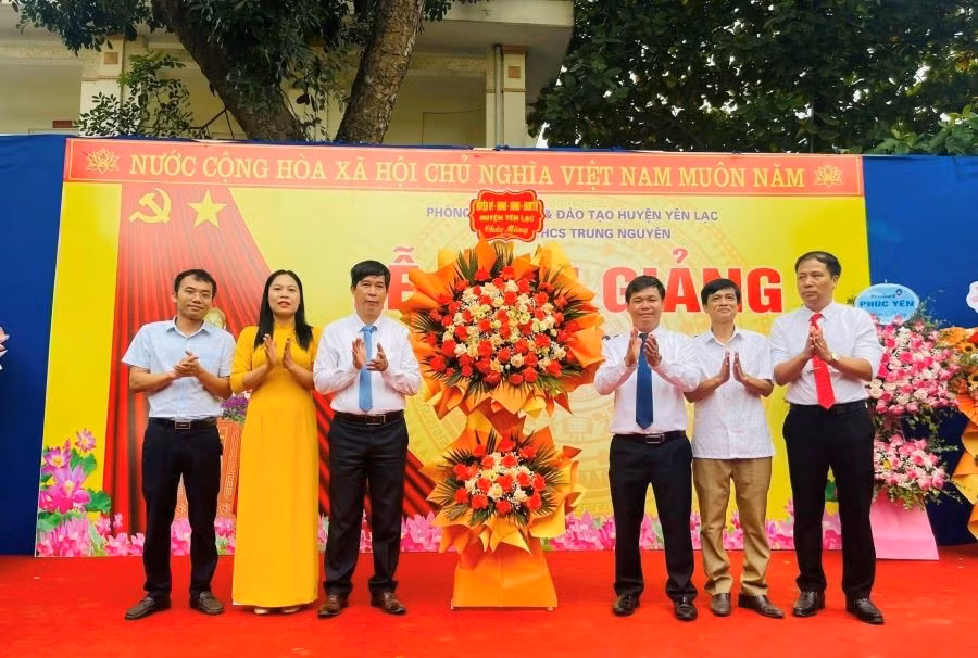 Đại diện Huyện ủy, HĐND, UBND huyện Yên Lạc (bên phải) tặng hoa chúc mừng thầy và trò trường THCS Trung Nguyên nhân dịp khai giảng năm học mới.