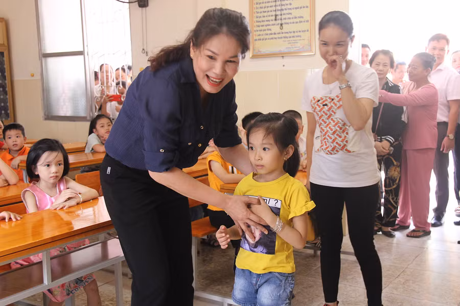 Cô bé còn bỡ ngỡ khi rời tay mẹ, được cô giáo đón vào lớp.