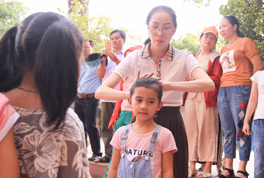 Cô giáo buộc lại tóc gọn gàng cho học sinh trước khi vào lớp.