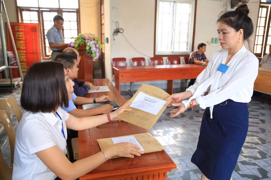 Giám thị nhận túi đựng hồ sơ dự thi của thí sinh
