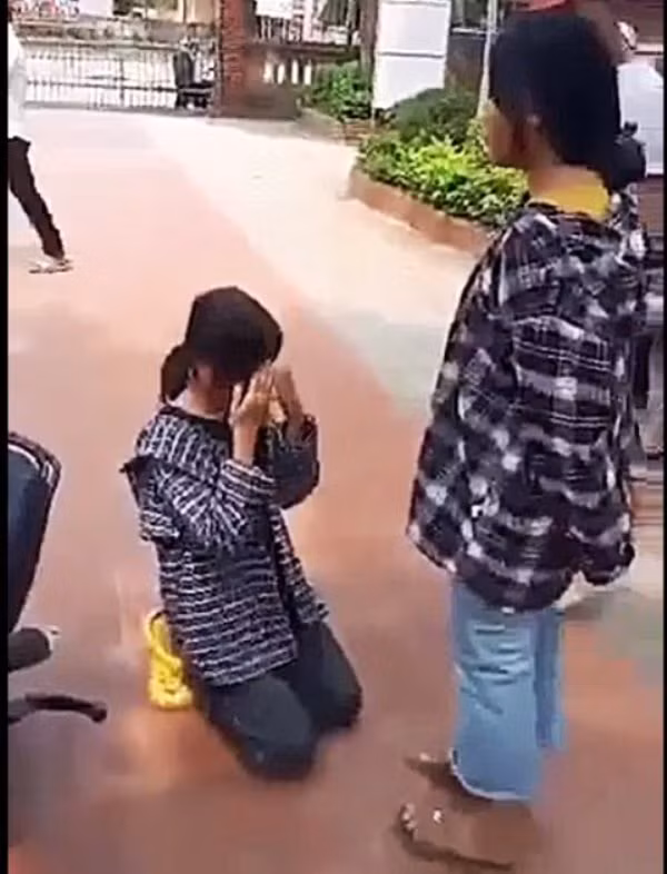 Nữ sinh bị bắt quỳ gối xin lỗi bạn ở sân trường. Ảnh: Cắt từ clip.