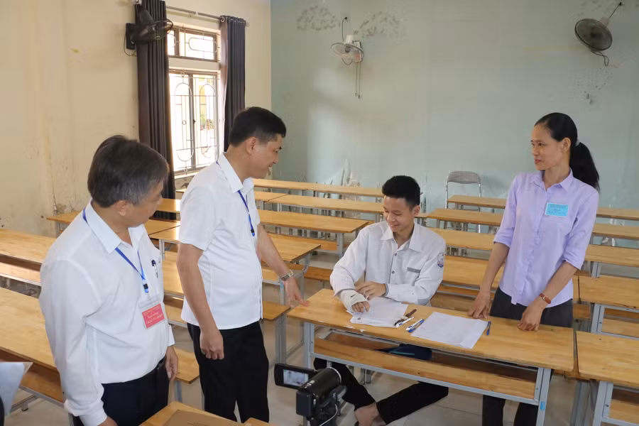 Lãnh đạo Sở GD&amp;ĐT Nghệ An động viên thí sinh bị gãy tay phải, dự thi tại phòng thi riêng có máy quay, máy ghi âm ghi lại quá trình làm bài. Ảnh: Hồ Lài.