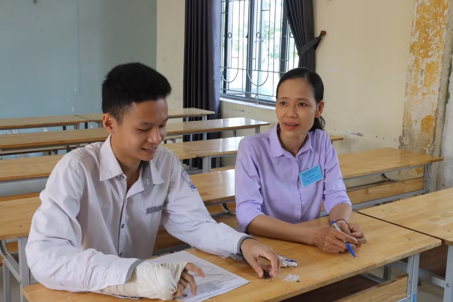 Em Nguyễn Công Đạt bị gãy tay phải, dự thi môn Ngữ văn với giám thị chép bài hộ. Ảnh: Hồ Lài.