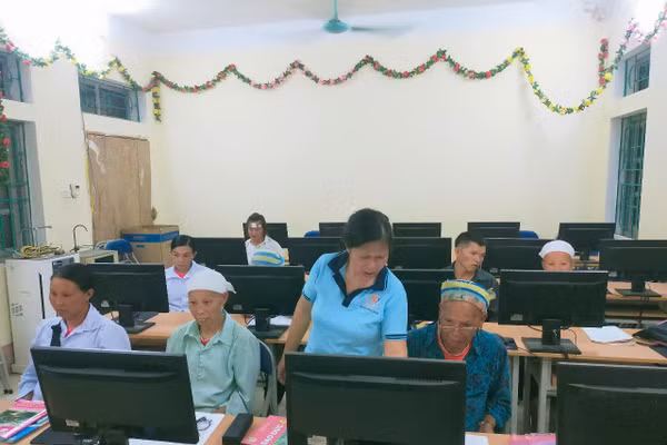 Cụ Phùng Mùi Coi (ngoài cùng bên phải), 68 tuổi, xóm Lũng Quáng, xã Huy Giáp (Cao Bằng) được cô giáo hướng dẫn học tập cùng máy tính.