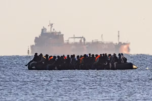 Xuồng nhỏ chở người di cư hướng về Dover, phía sau là một tàu chở hàng rời, gần Calais, Pháp, ngày 6/9/2026.