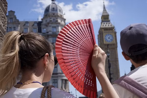Du khách dùng quạt trước tòa nhà Quốc hội trong đợt nắng nóng ở London, Anh, ngày 19/6/2026.