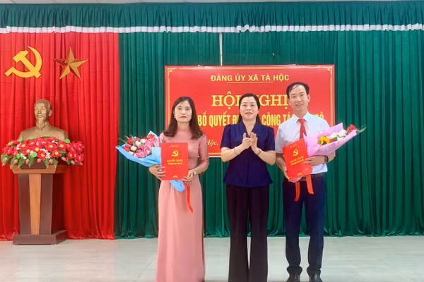 Bà Cầm Thị Khay (đứng giữa) trao quyết định và tặng hoa chúc mừng ông Ngô Văn Bích và bà Đào Thị Xuân.